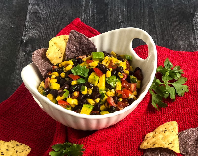 Top view of Cowboy Caviar in a white bowl on a red cloth.
